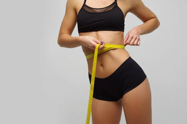 Menina esbelta em lingerie mede linha de cintura, bela figura — Fotografia de Stock