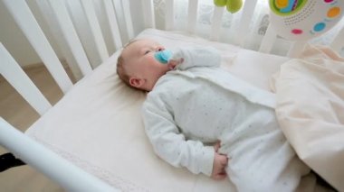 Beyaz ahşap beşik içinde yalan emzik ile şirin 3 aylık bebek çocuk portresi. Bebeğin yüzünde kamera tava