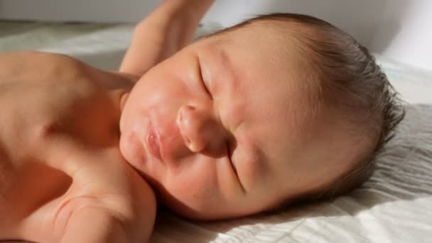 Primer plano de bebé recién nacido llorando acostado en la cama bajo los rayos del sol — Vídeos de Stock