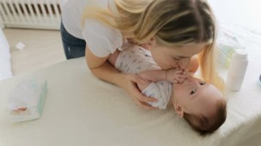 Mutlu genç anne konuşmak ve 3 aylık bebeğini tablo değiştirilmesi hakkında yalan öpüşme