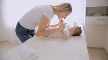 Konuşmak ve tablo değiştirilmesi hakkında yalan onun bebek çocuk ile oynarken genç bakan anne