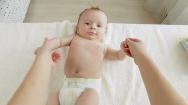 Genç anne onun sevimli 3 aylık erkek bebek tablo değiştirilmesi hakkında yalan ile oynarken POV shot