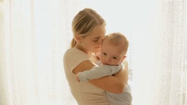 Mutlu genç anne büyük parlak güneş ışınları penceresinde, onun 3 aylık erkek bebek tutan sıcak atış tonda