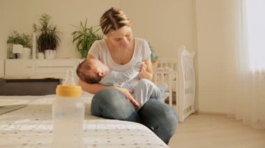 Mutlu genç anne bebeğini yatağında uyumak için sallanan Dolly atış