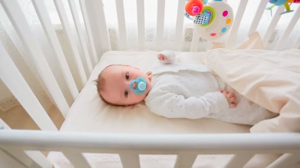 Junge Mutter streichelt ihren kleinen Sohn, der im Kinderbett liegt — Stockvideo