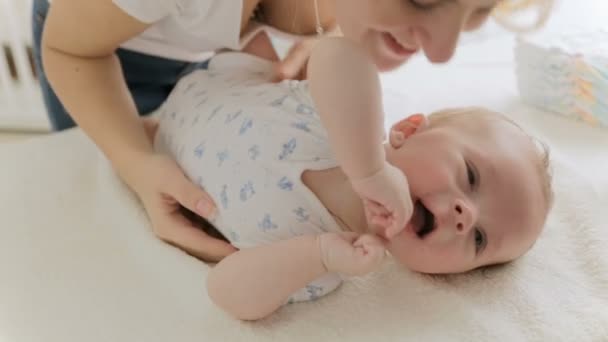 Feliz madre joven cosquillas y jugando con su adorable bebé niño — Vídeo de stock