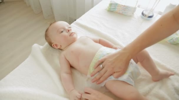 Close-up shot van de jonge moeder luiers aan haar 3 maanden oude babyjongen liggend op tafel — Stockvideo