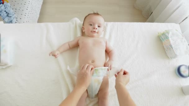 POV ung mamma tar smutsiga blöjor av förtjusande baby pojke liggande på bordet — Stockvideo