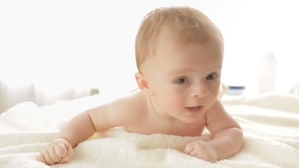Close-up shot van moeder helpt haar babyjongen die viel terwijl kruipen op bed — Stockvideo