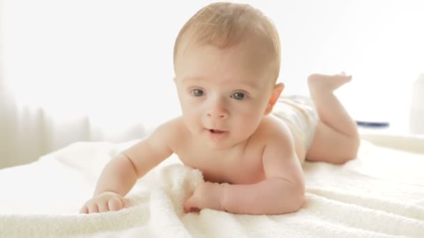 Adorable 3 months old baby boy crawling on bed in front of big window — Stock Video