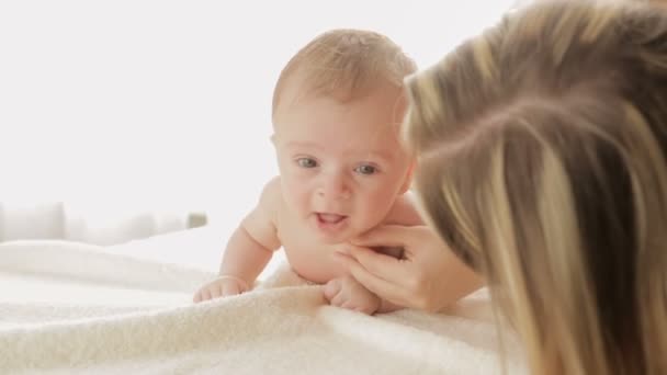 Close-up shot van de jonge moeder met haar 3 maanden oude babyjongen kruipen op bed — Stockvideo