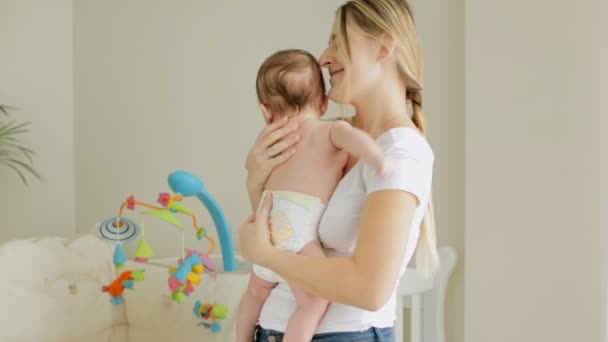 Mooie lachende vrouw met haar 3 maanden oude babyjongen op handen in de slaapkamer van kind — Stockvideo