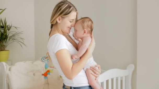 Glad ung mamma krama hennes 3 månader gammal baby son på sovrum — Stockvideo