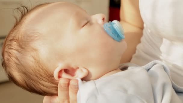 Close-up shot van mooie 3 maanden oude babyjongen slaap aan moeders handen — Stockvideo