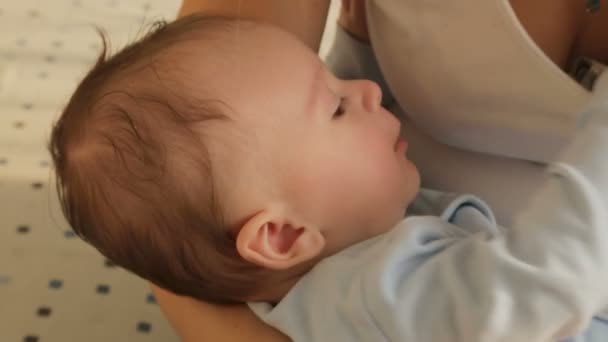 Nahaufnahme eines süßen Jungen, der auf den Händen der Mutter einschläft — Stockvideo