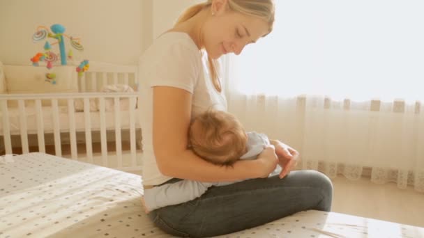 Steadicam-Aufnahmen der schönen fürsorglichen Mutter, die ihr Baby auf den Händen schaukelt. Frau sitzt bei strahlendem Sonnenschein auf — Stockvideo