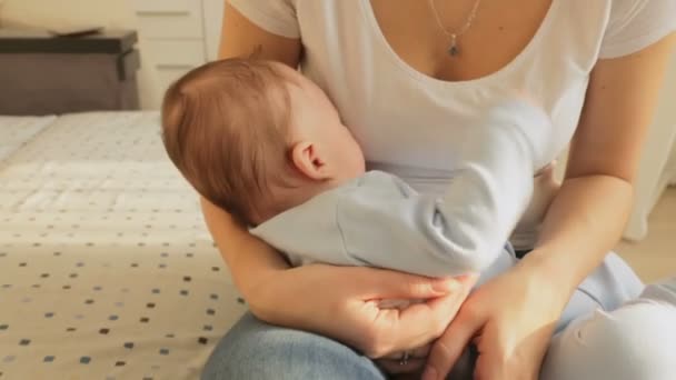 Steadicam voler autour plan de belle femme berçant son bébé pour dormir sur le lit — Video