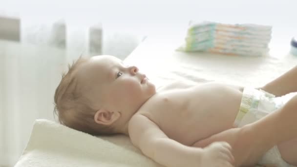 Primer plano de la madre sosteniendo adorable bebé niño en la mesa y cambiando pañales — Vídeo de stock