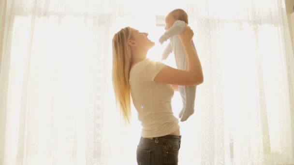 Mutlu genç anne ve büyük pencereden parlayan güneş ışınları, erkek bebek — Stok video