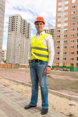 Genç gülümseyen ayakta binalar inşaat altında mimar