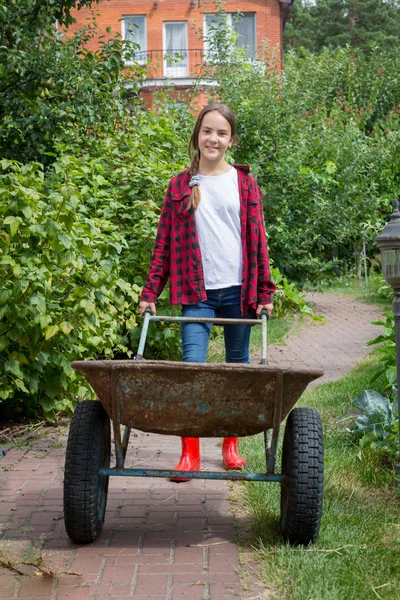 Joven chica sonriente con carretilla trabajando en el jardín — Foto de Stock