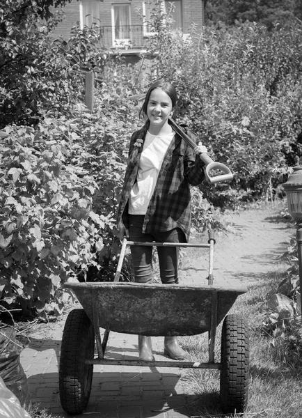 Black and white photo of teen girl posing with wheelbarrow at ga — Stock Photo, Image