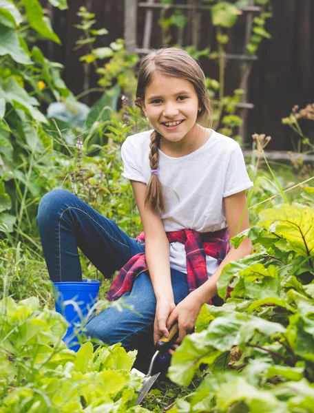 Chica sonriente que trabaja en el jardín y la excavación de lettu verde fresco — Foto de Stock