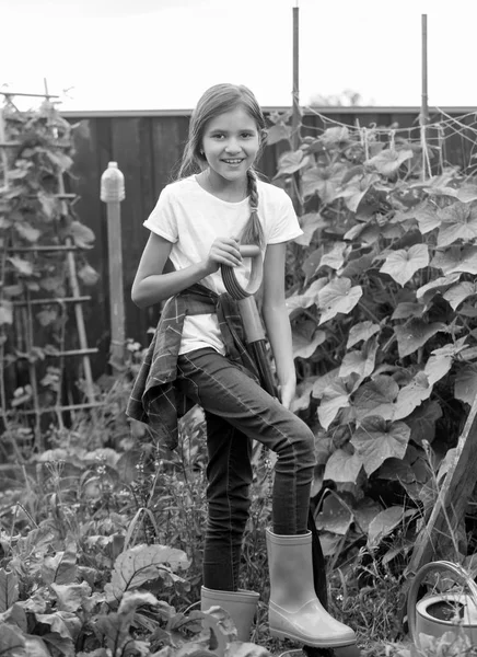 Черно-белое изображение симпатичной 10-летней девочки, работающей в саду — стоковое фото