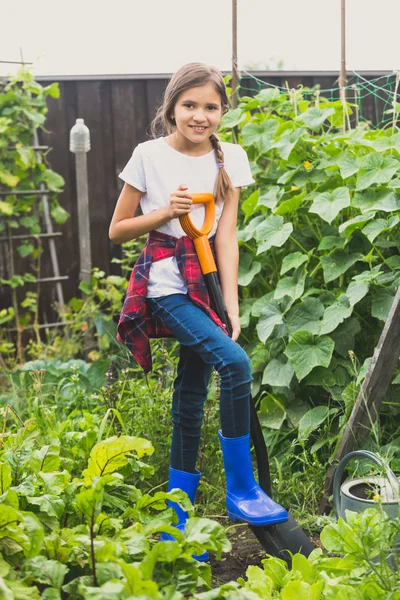 Счастливая девушка работает в саду с лопатой — стоковое фото