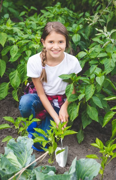 Bella ragazza adolescente sorridente che lavora in giardino con spinta a mano — Foto Stock