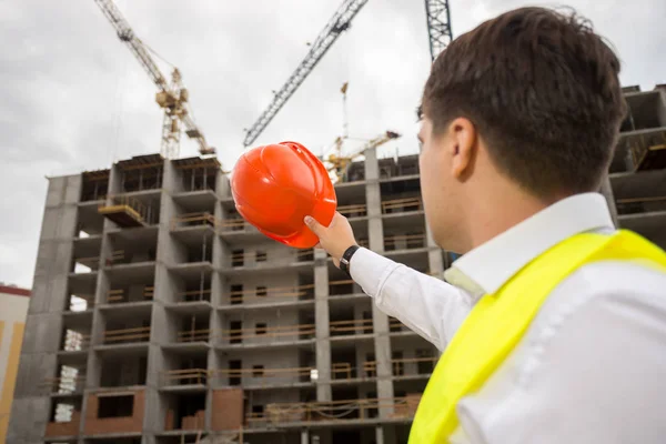 Inżynier budowy młodych, wskazując na budynku w trakcie budowy — Zdjęcie stockowe