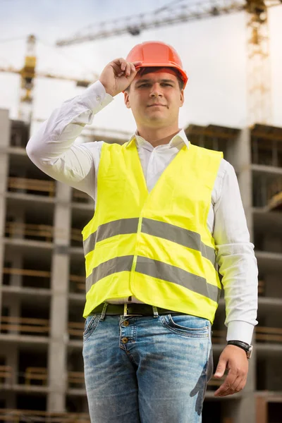 Stilig leende ingenjör i hardhat poserar mot arbetande nackdelar — Stockfoto