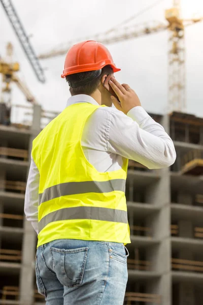 Construction engineer talking by phone and looking on building s — Stock Photo, Image