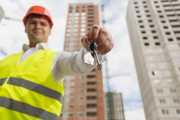 Інженер на будівельному майданчику, що показує ключ від нового будинку — стокове фото