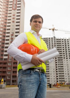 Genç inşaat mühendisi hardhat tutan güvenlik yeleği