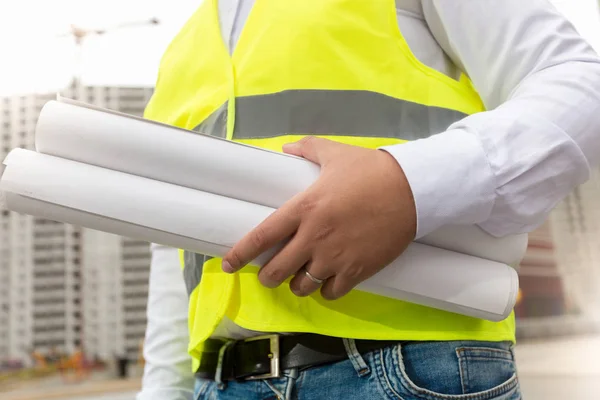 Ingeniero de construcción sosteniendo planos en la obra — Foto de Stock