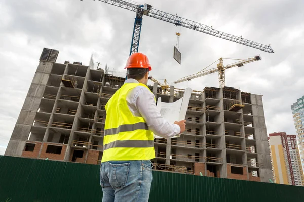 Giovane ispettore ingegnere che guarda l'edificio in costruzione — Foto Stock