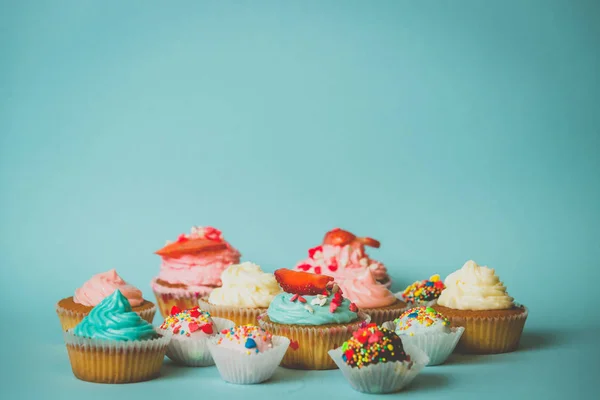 Cupcakes mit Erdbeere und Bonbons mit Streusel auf blauem Rücken — Stockfoto