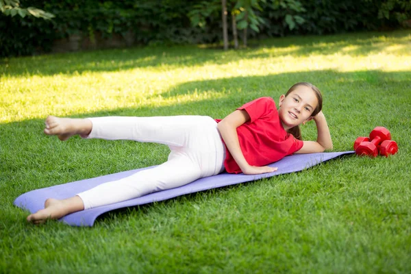 Młoda dziewczyna uśmiechający się ćwiczenia na trawie w parku — Zdjęcie stockowe