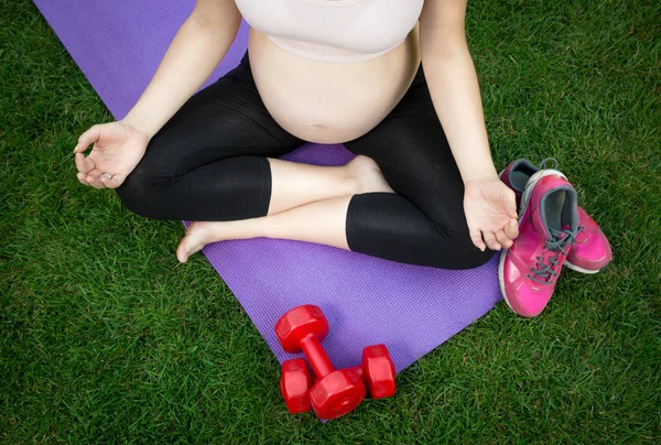 Imagen de primer plano de la mujer embarazada meditando en la esterilla de fitness outdoo — Foto de Stock