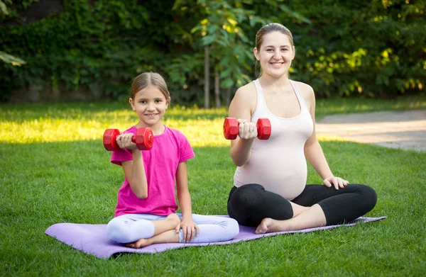 Unga gravida modern utövar yoga på gräs på park — Stockfoto