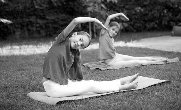 Dwie piękne dziewczyny, rozciąganie i robi joga na trawie — Zdjęcie stockowe