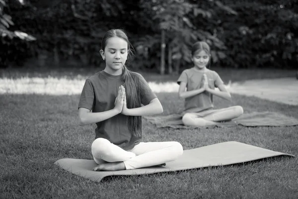 Czarno-biały obraz dwa słodkie dziewczyny praktykowania jogi w parku — Zdjęcie stockowe