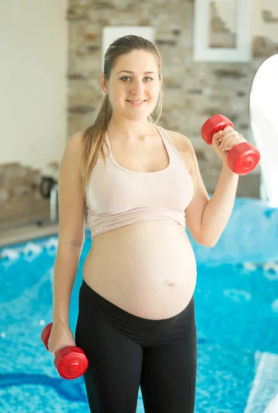 Mujer esperando bebé haciendo ejercicio con pesas en el gimnasio — Foto de Stock