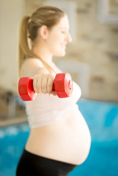 Giovane donna incinta che si esercita con i manubri in palestra — Foto Stock