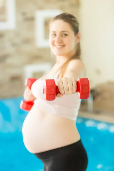 Young pregnant woman lifting dumbbell at gym — Stock Photo, Image