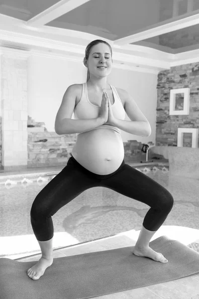 Preto e branco imagem de sorrindo grávida fazendo ioga no gy — Fotografia de Stock