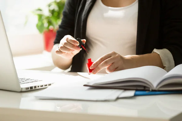 Closeup of young businesswoman painting fingernails at office ta — Stock Photo, Image