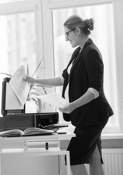 Молодая предпринимательница в черном костюме делает копии документов на — стоковое фото