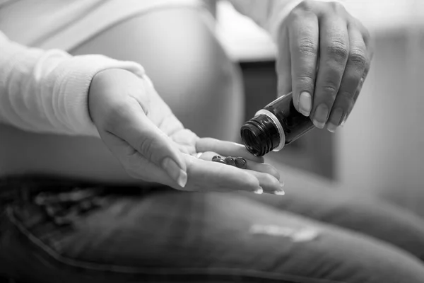 Монохромне крупним планом фото вагітної жінки, що тримає таблетки на руці — стокове фото
